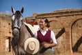 Woman horsewoman, young and beautiful, with hat, next to her horse, in the countryside next to a ruined building. Concept horse