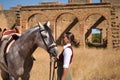 Woman horsewoman, young and beautiful, next to her horse, in the countryside next to a ruined building. Concept horse riding,