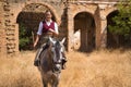 Woman horsewoman, young and beautiful, standing, riding her horse, in the field next to a ruined building. Concept horse riding,