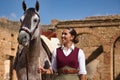 Woman horsewoman, young and beautiful, with stick, next to her horse, in the countryside next to a ruined building. Concept horse