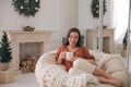 Woman with hot drink resting in comfortable papasan chair at home Royalty Free Stock Photo