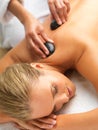 Woman, hot stone massage and spa with hands of masseuse, peace and treatment for destress at luxury resort. Serene, zen