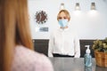 Woman hotel receptionist wearing medical mask to protect from coronavirus infection