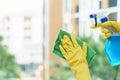 Woman housekeeper cleaning the mirror with green cloth.