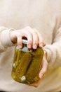 Woman housewife hand holding glass jar of pickled cucumbers. Domestic preparation pickling and canning of vegetables, winter Royalty Free Stock Photo