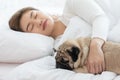 Woman hug dog pug breed and sleep in cozy white bedroom Royalty Free Stock Photo