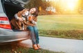 Woman huges her dog with shawls sitting together in car trunk