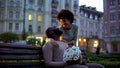 Woman hugging boyfriend, looking with love, holding flowers, romantic date