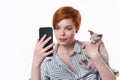 Woman hugging cat, having video-call holding smart phone in hand shooting selfie on camera Royalty Free Stock Photo