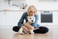 Woman hugging little dog while posing on floor in kitchen Royalty Free Stock Photo