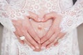 A woman hugging a lovely pregnant tummy. Hands in the shape of a heart