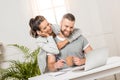 Woman hugging man that sitting at workplace at home