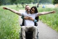 Woman hugs joyful man in wheelchair in park