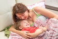 A woman hugs little daughter in bed waking up