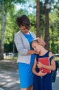 A woman hugs an unhappy schoolgirl daughter