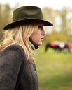 Woman in hunting hat with horses in background