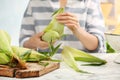 Woman husking corn at table, focus