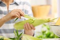 Woman husking corn at table