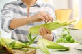 Woman husking corn at table,