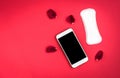 Woman hygiene protection or sanitary pads with rose petals and mobile phone on red background. Menstrual cycle tracking