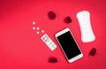 Woman hygiene protection or sanitary pads with rose petals and mobile phone on red background. Menstrual cycle tracking