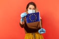 Woman in hygienic face mask and gloves showing European Union flag, concept of coronavirus pandemic threat Royalty Free Stock Photo