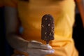 Woman with ice cream covered chocolate and almonds in hand on dark backg