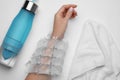 Woman with ice pack, bottle of water and towel on white background, top view. Heat stroke treatment