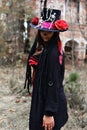 A woman in the image of Baron Saturday poses against the backdrop of an old ruined brick building. The model is dressed Royalty Free Stock Photo