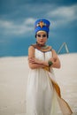 Woman in image of egyptian queen Nefertiti stands in desert with whip in her hand Royalty Free Stock Photo