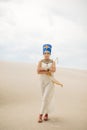 Woman in image of egyptian queen Nefertiti walks through sandy desert Royalty Free Stock Photo