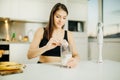 Woman with immersion blender making banana chocolate protein powder milkshake smoothie.Adding a scoop of low carb whey protein mix Royalty Free Stock Photo