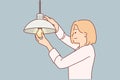 Woman independently changes burned-out light bulb in order to achieve high-quality lighting in house