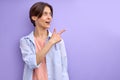 Excited woman indicates finger at side on empty space advising product for buyers