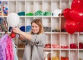 a woman inflates of helium from a white balloon.