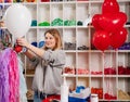 a woman inflates of helium from a white balloon.