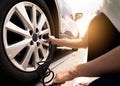 Woman inflates the tire. Woman checking tire pressure and pumping air into the tire of car wheel. Car maintenance service for Royalty Free Stock Photo