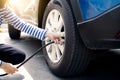 Woman inflates the tire. Woman checking tire pressure and pumping air into the tire of car wheel. Car maintenance service for