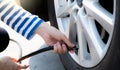 Woman inflates the tire. Woman checking tire pressure and pumping air into the tire of car wheel. Car maintenance service for