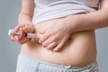 Woman is injecting hormones to belly with syringe.