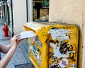 Woman insert a letter inside yellow la poste French mailbox Royalty Free Stock Photo