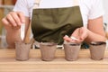 Woman inserting cards with names of vegetable seeds into peat pots at table, closeup