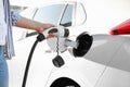 Woman inserting plug into electric car socket at charging station  closeup Royalty Free Stock Photo