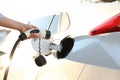 Woman inserting plug into electric car socket at charging station, closeup Royalty Free Stock Photo