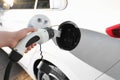 Woman inserting plug into electric car socket at charging station, closeup Royalty Free Stock Photo