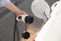 Woman inserting plug into electric car socket at charging station, closeup Royalty Free Stock Photo