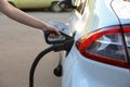 Woman inserting plug into electric car socket at charging station, closeup Royalty Free Stock Photo