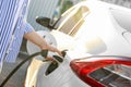 Woman inserting plug into electric car socket at charging station, closeup Royalty Free Stock Photo