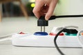 Woman inserting power plug into extension cord on floor indoors, closeup. Electrician`s equipment