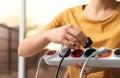 Woman inserting power plug into extension cord indoors. Electrician`s professional equipment